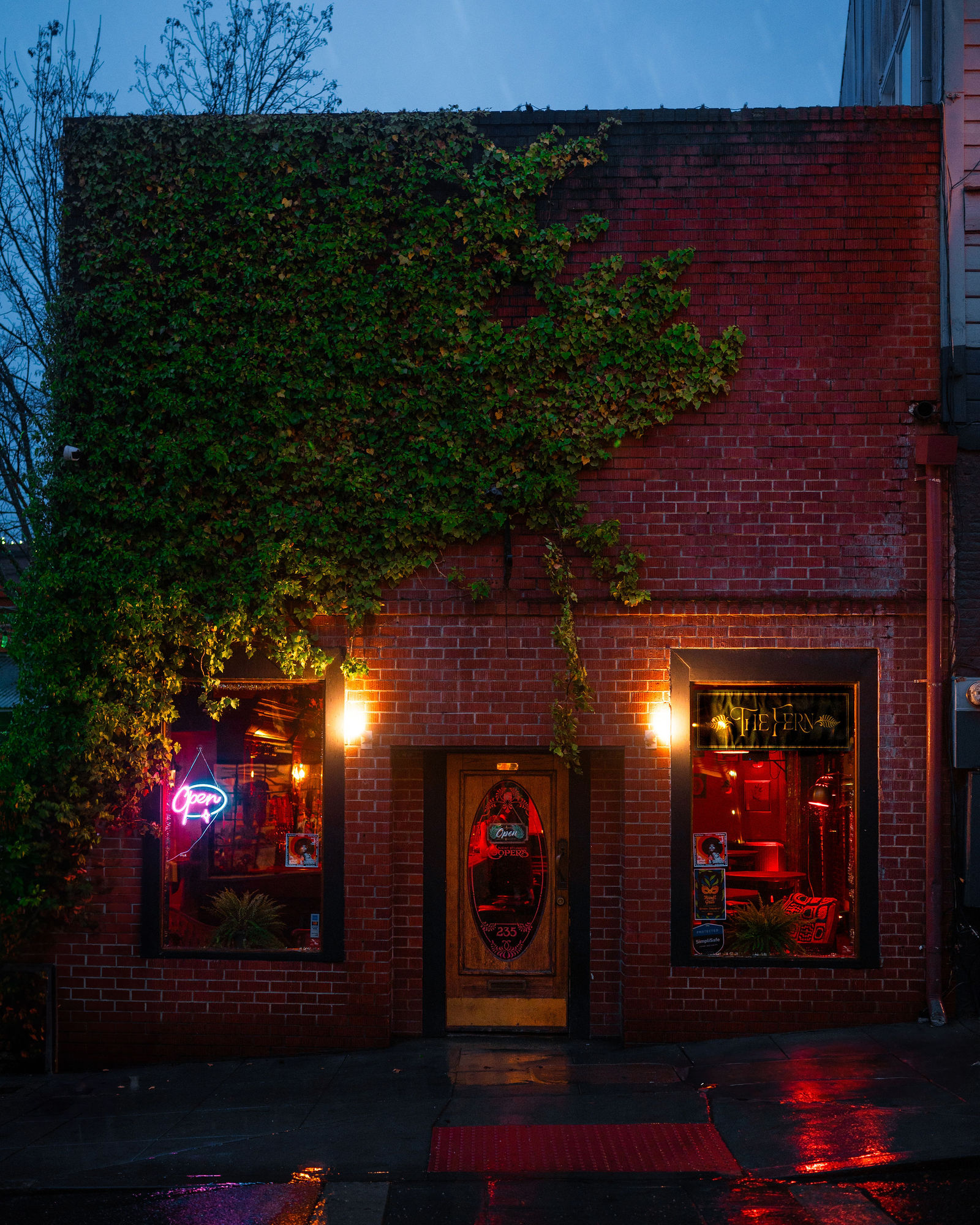 The ivy-covered brick façade of The Fern on Commercial Street, lit red from inside on a wet evening